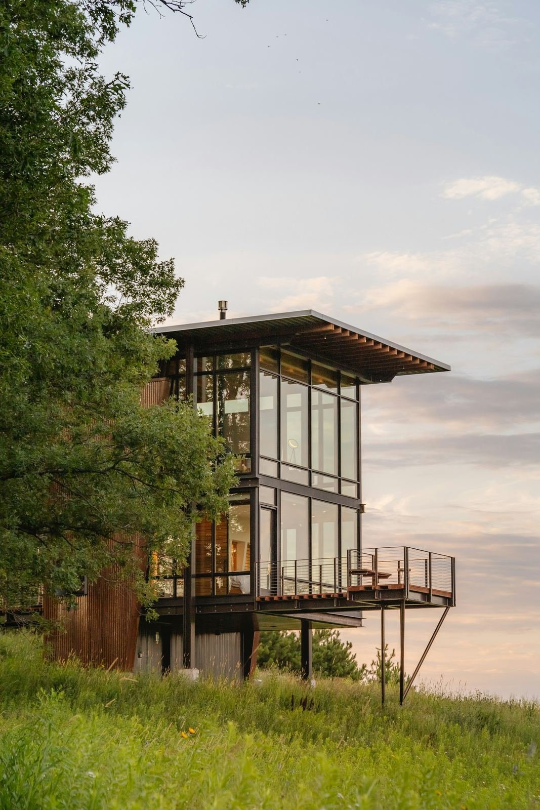 Two-level glass home on a hillside meadow